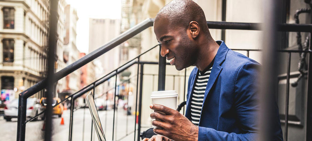 Man drinking coffee while on computer